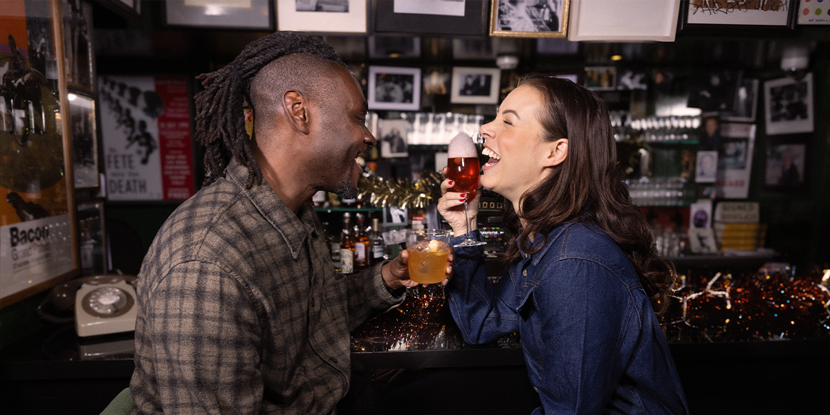 Couple laughing sat at a bar